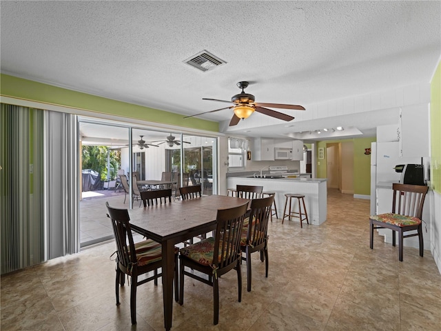 dining room featuring ceiling fan, sink, and a textured ceiling