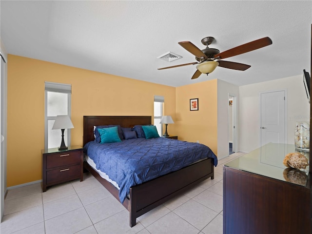 tiled bedroom with ceiling fan and a textured ceiling