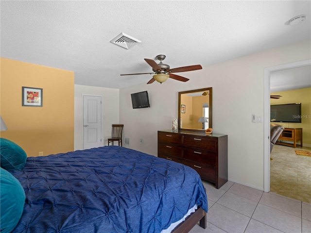 bedroom with ceiling fan, light tile patterned floors, and a textured ceiling