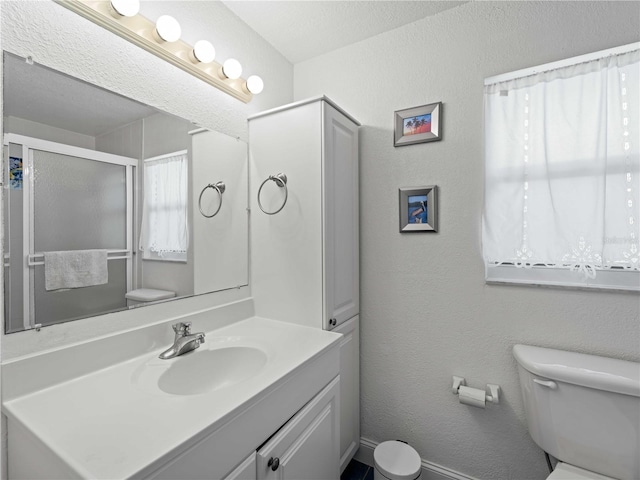 bathroom featuring walk in shower, vanity, toilet, and a textured ceiling