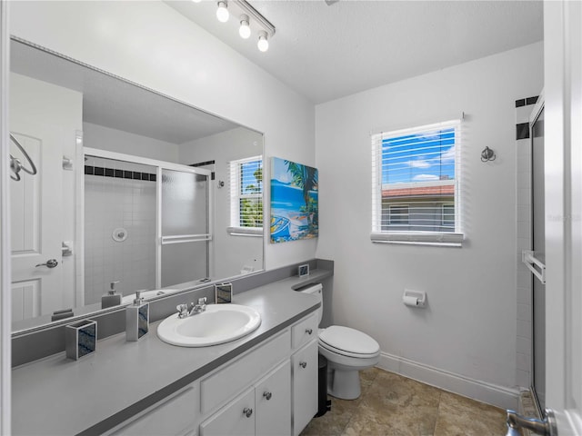 bathroom featuring a textured ceiling, vanity, toilet, and a shower with shower door