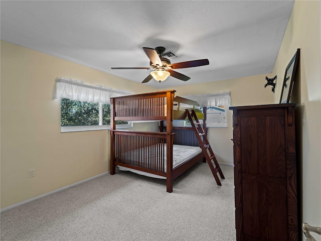 carpeted bedroom featuring ceiling fan and a textured ceiling