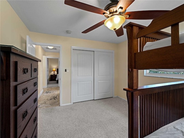 unfurnished bedroom with light carpet, ceiling fan, and a closet