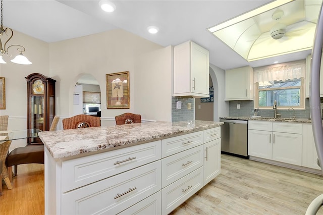 kitchen with light hardwood / wood-style floors, white cabinetry, stainless steel dishwasher, and hanging light fixtures