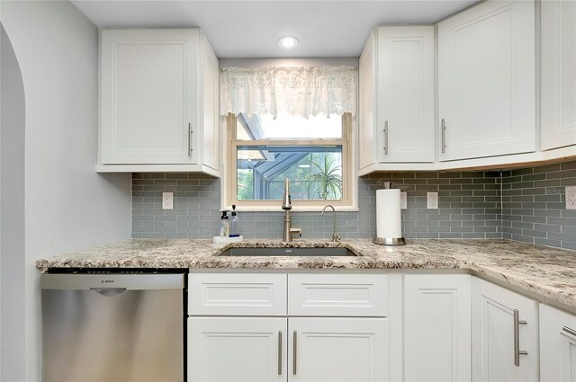 kitchen with dishwasher, backsplash, sink, light stone countertops, and white cabinetry