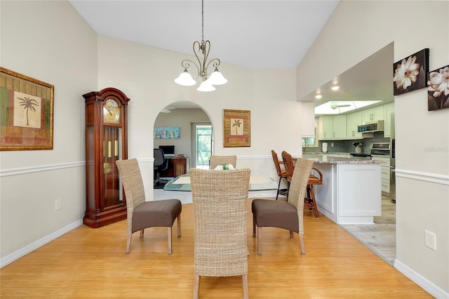 dining space featuring light hardwood / wood-style floors, lofted ceiling, and a chandelier