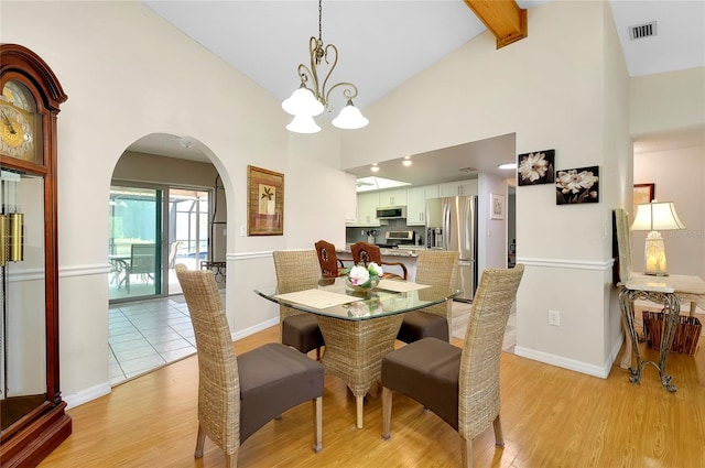 dining room featuring light hardwood / wood-style floors, high vaulted ceiling, beam ceiling, and an inviting chandelier