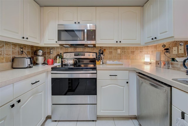 kitchen with decorative backsplash, stainless steel appliances, white cabinetry, and light tile patterned floors