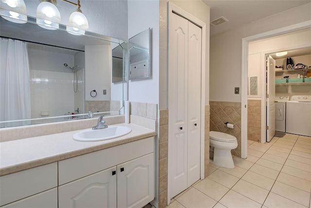 bathroom featuring vanity, tile patterned floors, separate washer and dryer, tile walls, and toilet