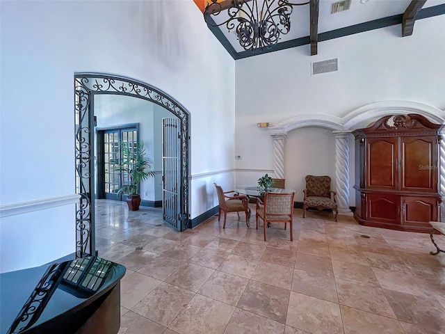 entrance foyer with high vaulted ceiling, beam ceiling, and a chandelier