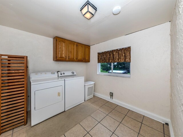 laundry room featuring cabinets, light tile patterned floors, and washer and dryer