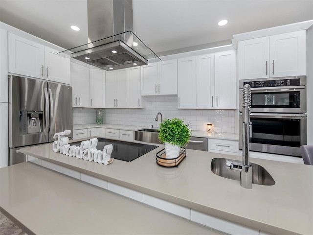 kitchen featuring island exhaust hood, appliances with stainless steel finishes, backsplash, and white cabinetry