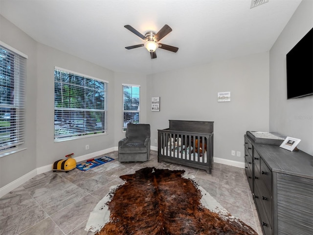 bedroom featuring ceiling fan and a nursery area