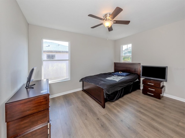 bedroom featuring ceiling fan, light wood-type flooring, and multiple windows