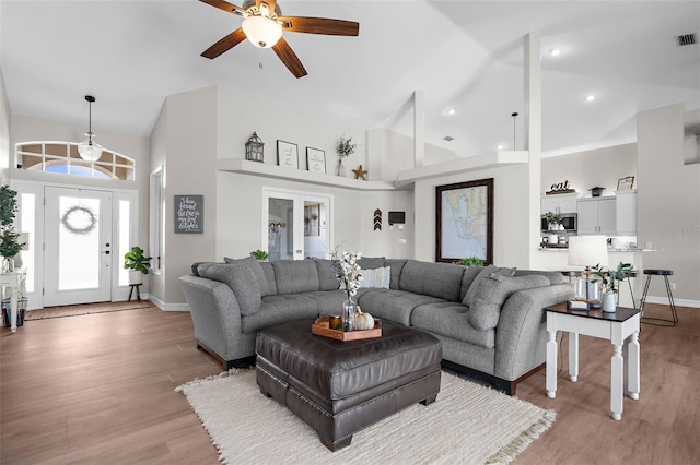 living room with ceiling fan, light wood-type flooring, french doors, and high vaulted ceiling