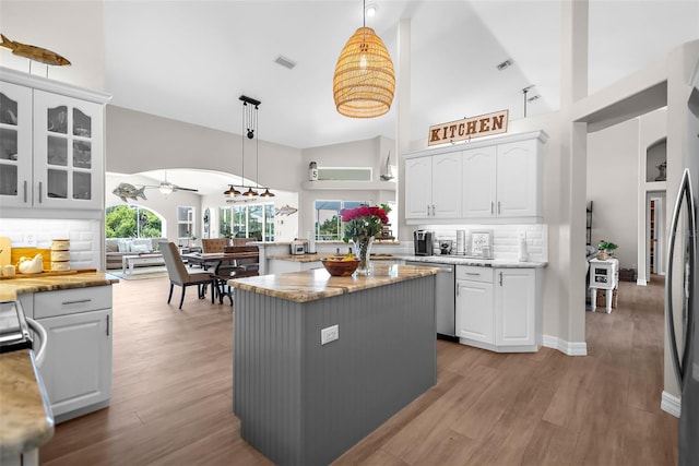 kitchen with hanging light fixtures, white cabinetry, a center island, and high vaulted ceiling