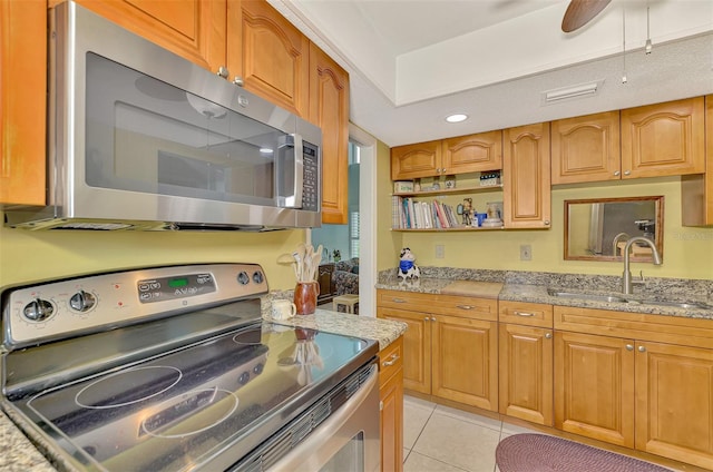 kitchen with light tile patterned flooring, sink, stainless steel appliances, and light stone counters