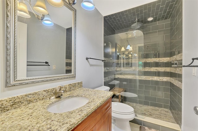 bathroom with a tile shower, vanity, toilet, and tile patterned floors