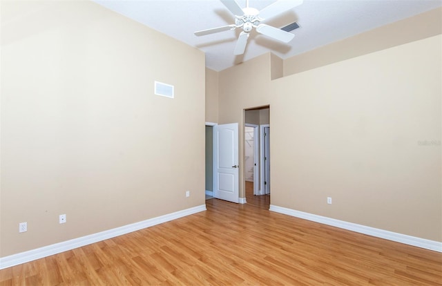 unfurnished bedroom with ceiling fan, a towering ceiling, and light hardwood / wood-style floors