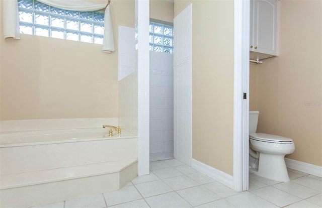 bathroom featuring tile patterned flooring, a healthy amount of sunlight, a washtub, and toilet