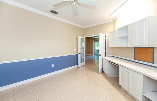 kitchen with ceiling fan, built in desk, white cabinets, crown molding, and light tile patterned floors