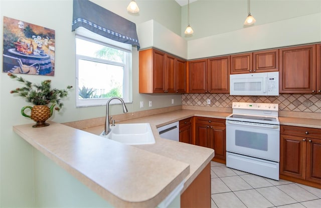 kitchen featuring white appliances, decorative light fixtures, sink, decorative backsplash, and kitchen peninsula