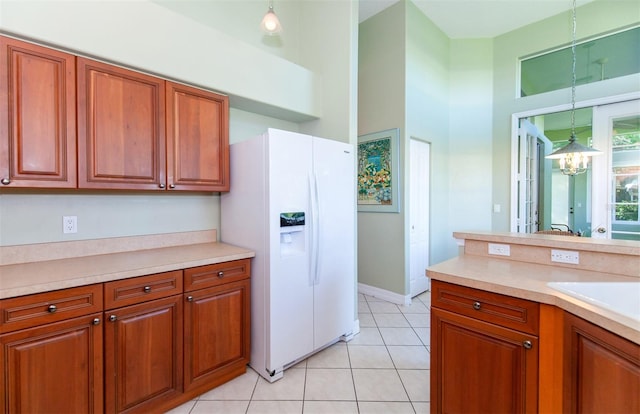 kitchen with light tile patterned flooring, an inviting chandelier, white fridge with ice dispenser, decorative light fixtures, and sink