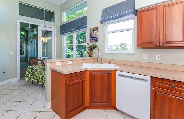 kitchen featuring sink, kitchen peninsula, hanging light fixtures, white dishwasher, and light tile patterned floors