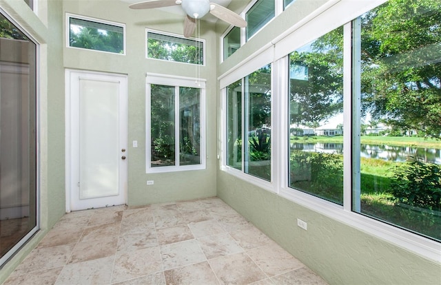 unfurnished sunroom featuring a water view and ceiling fan