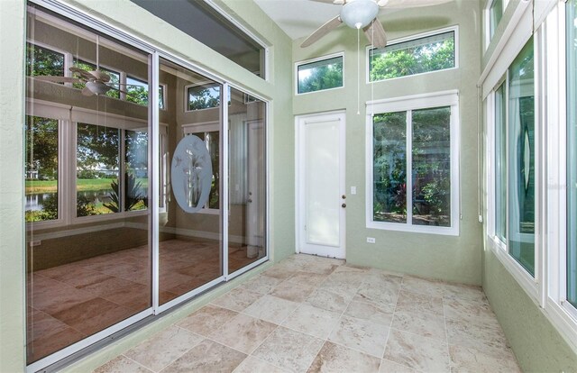 unfurnished sunroom with ceiling fan and a healthy amount of sunlight