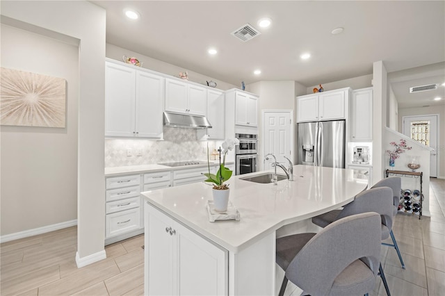 kitchen featuring a kitchen island with sink, stainless steel appliances, and white cabinets