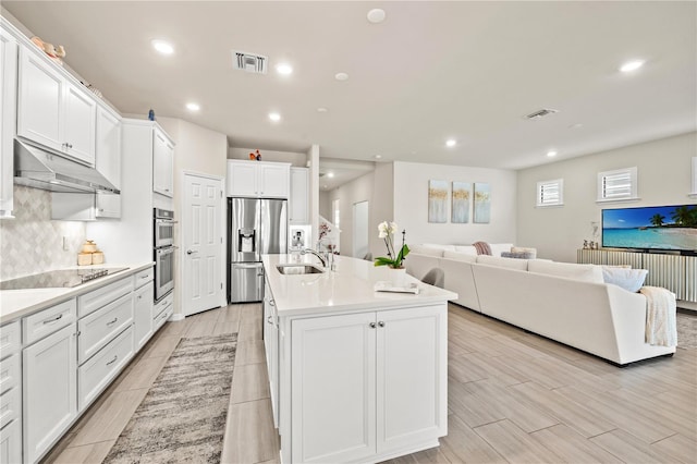 kitchen with a center island with sink, sink, stainless steel appliances, and white cabinets