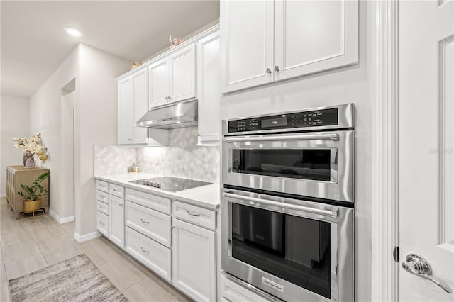 kitchen with black electric cooktop, white cabinetry, tasteful backsplash, light tile patterned floors, and double oven