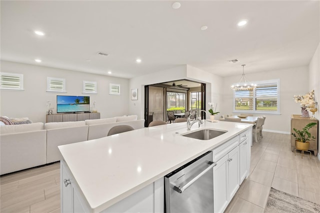 kitchen with dishwasher, plenty of natural light, white cabinetry, and an island with sink