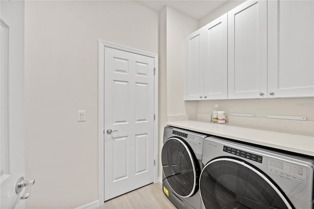 clothes washing area featuring cabinets, light hardwood / wood-style flooring, and separate washer and dryer