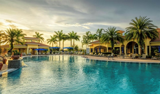 pool at dusk with a patio and pool water feature