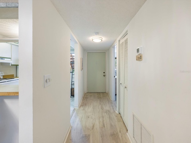 hall with light hardwood / wood-style flooring and a textured ceiling