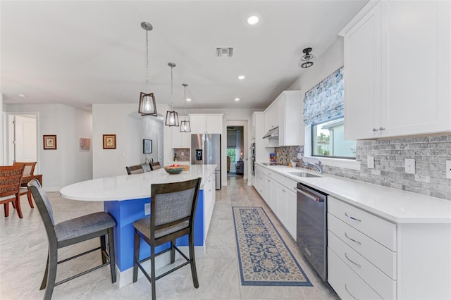 kitchen featuring white cabinets, a kitchen island, backsplash, stainless steel appliances, and a kitchen bar