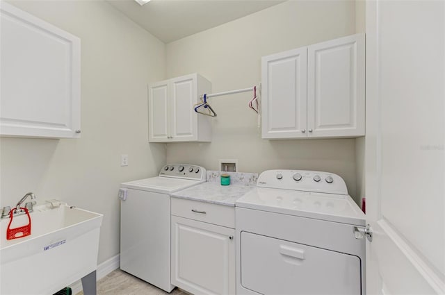 laundry area featuring cabinets, light wood-type flooring, separate washer and dryer, and sink