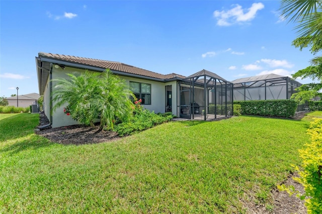 back of house featuring a lawn and glass enclosure