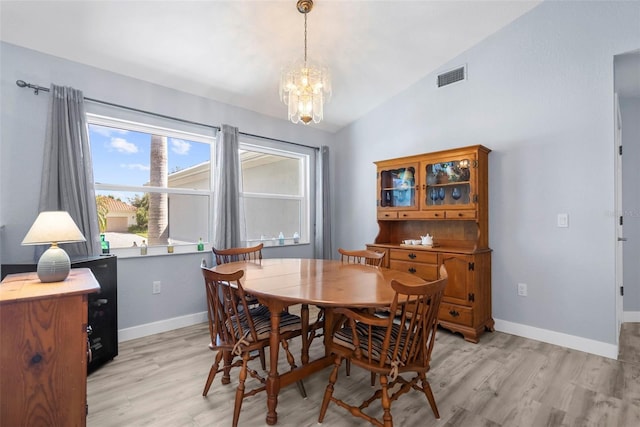 dining room with light hardwood / wood-style floors, lofted ceiling, and a chandelier