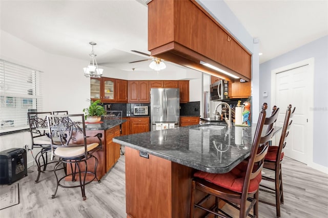 kitchen with a breakfast bar, light wood-type flooring, sink, decorative backsplash, and stainless steel appliances