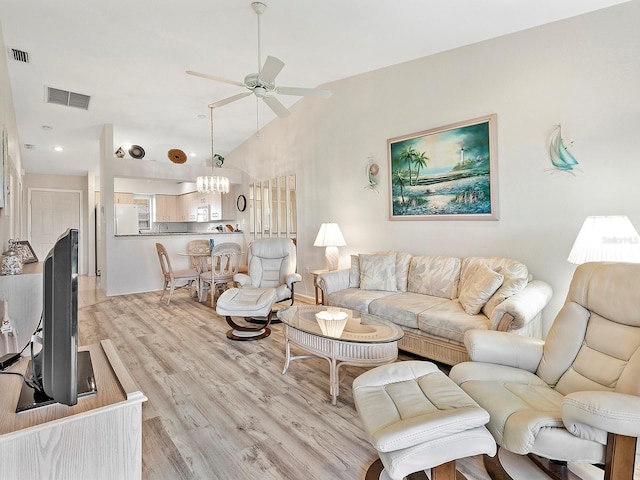 living room with ceiling fan with notable chandelier, vaulted ceiling, and light hardwood / wood-style flooring