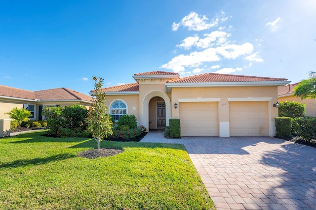 mediterranean / spanish-style home with stucco siding, a tiled roof, a front yard, and decorative driveway