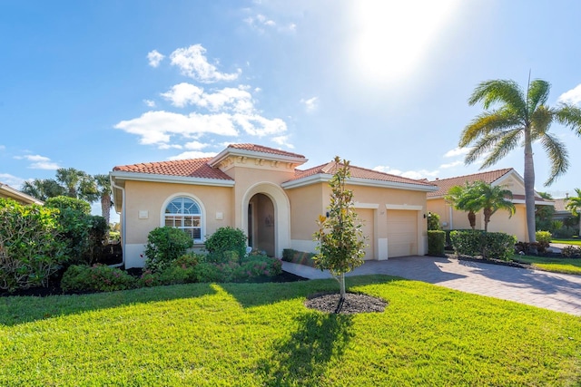 mediterranean / spanish-style house featuring decorative driveway, an attached garage, a front yard, a tile roof, and stucco siding