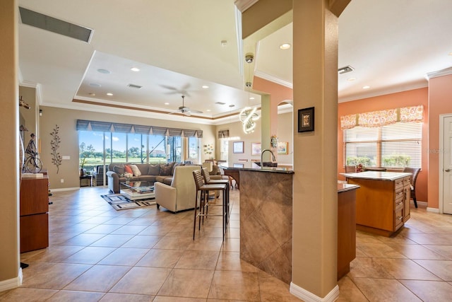 interior space featuring a wealth of natural light, visible vents, a raised ceiling, and a ceiling fan