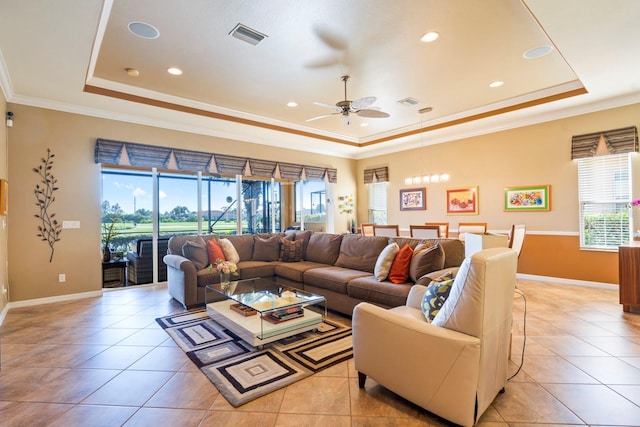 living room featuring ceiling fan with notable chandelier, a raised ceiling, crown molding, and light tile patterned floors