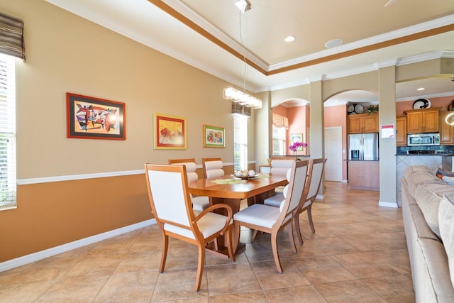 dining room featuring plenty of natural light, baseboards, crown molding, and arched walkways