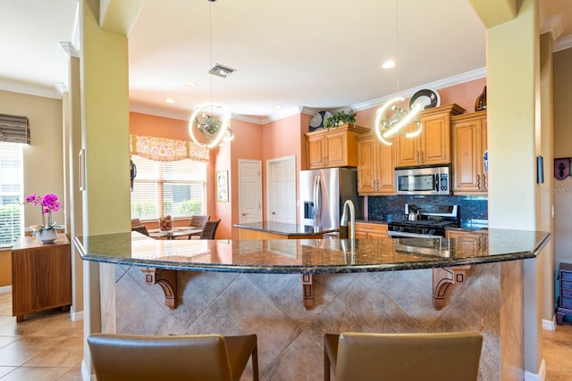 kitchen with a breakfast bar area, light tile patterned floors, pendant lighting, stainless steel appliances, and crown molding