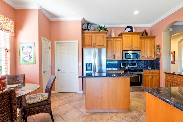 kitchen featuring dark stone countertops, appliances with stainless steel finishes, ornamental molding, and tasteful backsplash